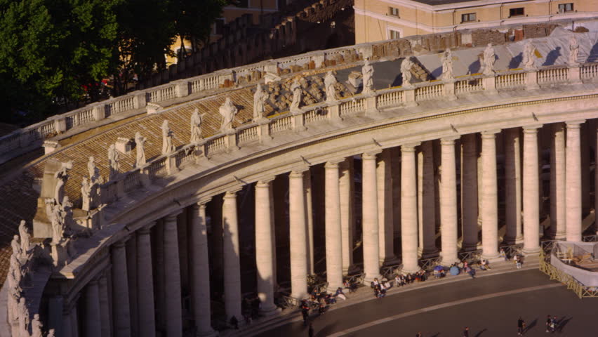 Tourists among row of columns lining the piazza of St Peter's Basilica