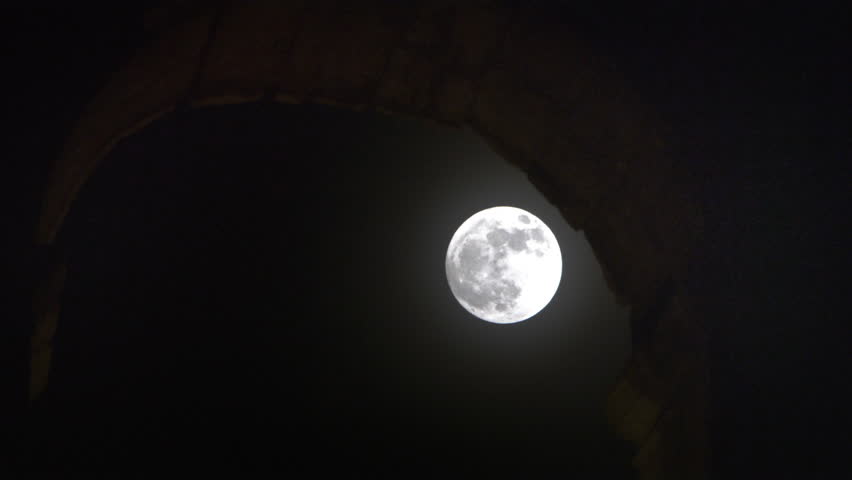 Time lapse of full moon hiding behind arch 