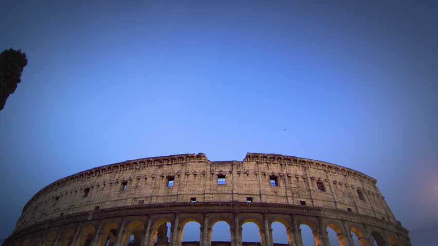 Tilt down from sky to illuminated Colosseum at night