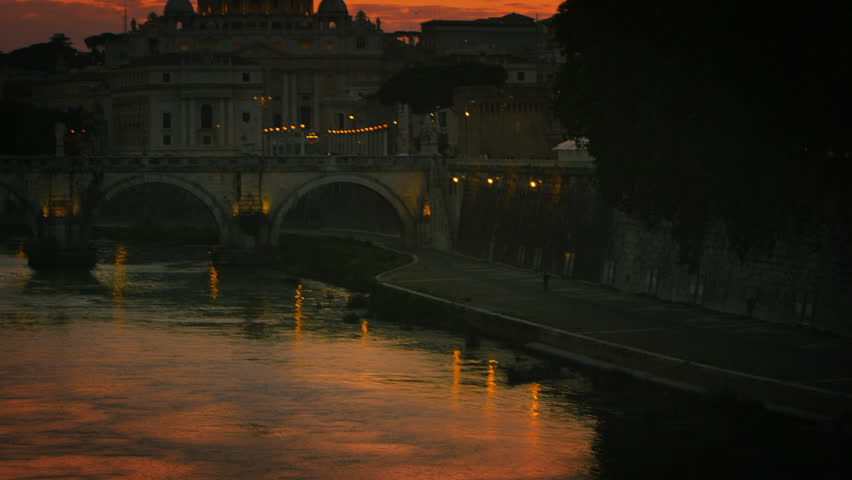 Slight tilt up and pan of Ponte Sant Angelo and St Peters Basilica at dusk