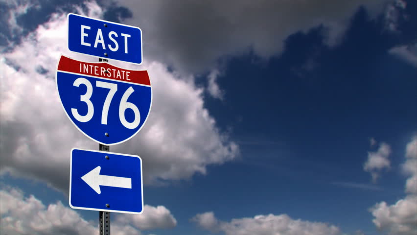 An Interstate sign with time lapse clouds.