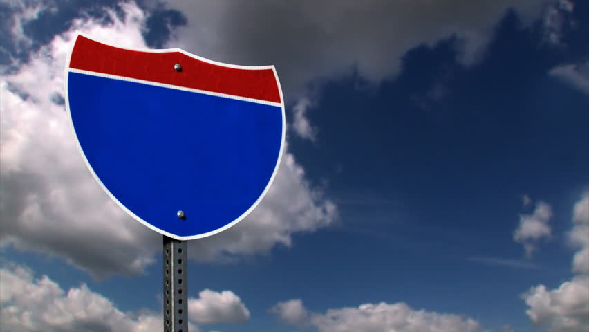 A blank Interstate sign with time lapse clouds.