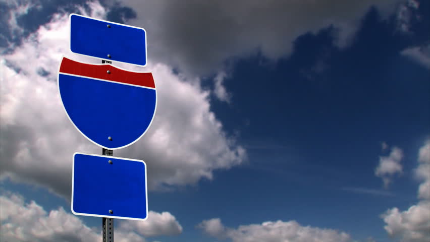 A blank Interstate sign with time lapse clouds.