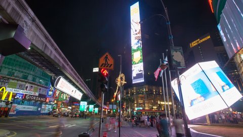 KUALA LUMPUR, MALAYSIA - FEBRUARY 5, 2014: Night scene of Bukit Bintang shopping district in Kuala Lumpur with tourists and shoppers, LRT train, and moving advertising LED lights time lapse. 