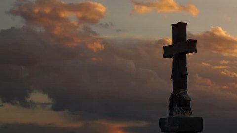 Timelapse of stone cross with golden sunset clouds