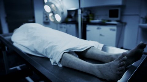 Dead male body laid out on an autopsy table comes back to life