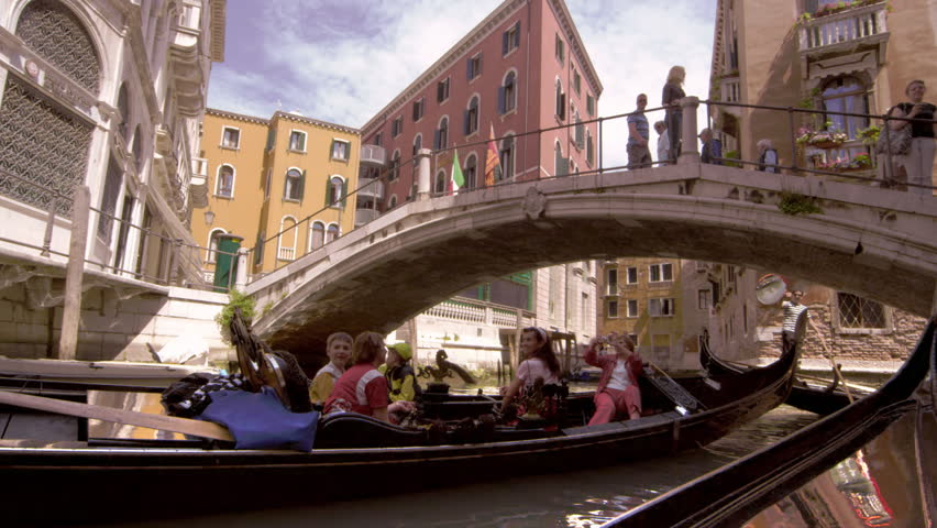 VENICE, ITALY - MAY 2, 2012: Gondola passes beneath pedestrian bridge