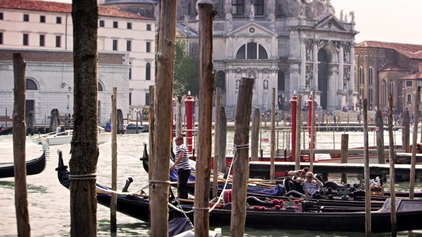 VENICE, ITALY - MAY 2, 2012: Docked gondolas and their gondoliers