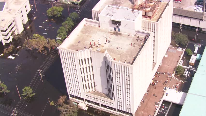 Rescue Flood Helicopter City. prisoners on roof of prison waiting for evacuation. Wide shot of flooded city of New Orleans.