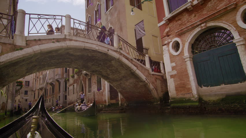 VENICE, ITALY - MAY 2, 2012: Gondolas pass under a bridge in slow motion