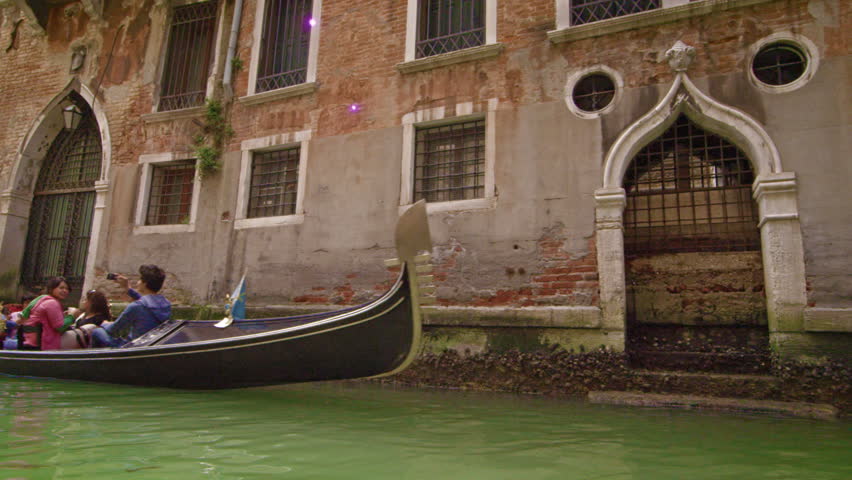 VENICE, ITALY - MAY 2, 2012: Gondolier guiding boat down canal in slow motion