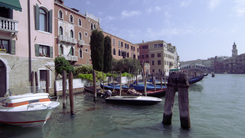 VENICE, ITALY - MAY 4, 2012: Docked gondolas pass on Grand Canal