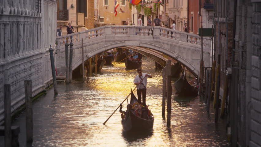 VENICE, ITALY - MAY 3, 2012: Shot of a gondola in a canal with a bridge behind.