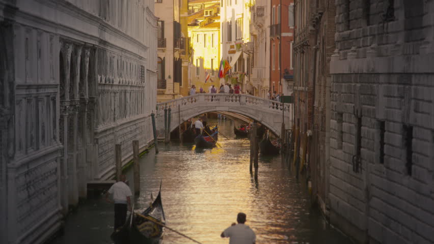 VENICE, ITALY - MAY 3, 2012: Shot of several gondolas in a canal with a bridge.
