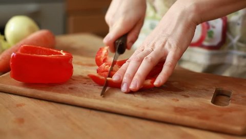 Woman hands slicing sweet Red Bell Pepper on a wooden cutting board (HD, high definition 1080p, 1920x1080) beautiful shot with soft focus. Healthy food concept.
