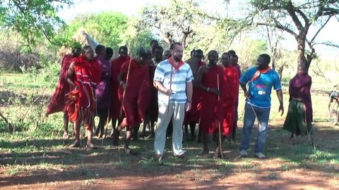 NGORONGORO, KIGALI, TANZANIA - CIRCA DEC, 2011: People of Maasai tribe during wedding ceremony jump and sing. Caucasian people take part in wedding ceremony with Masai warriors, Tanzania