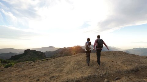 Freedom - Happy couple cheering and running in nature. Hiking man and woman raising arms excited in celebration outdoors. Hikers at sunset in mountain by Roque Nublo, Gran Canaria, Canary Islands
