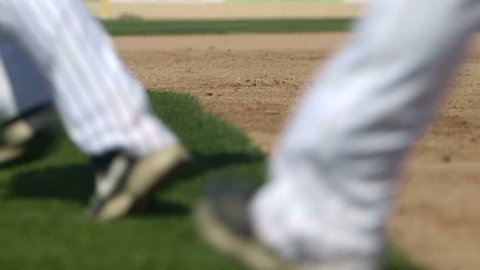A team of baseball players run from the field toward the dugout in slow motion.