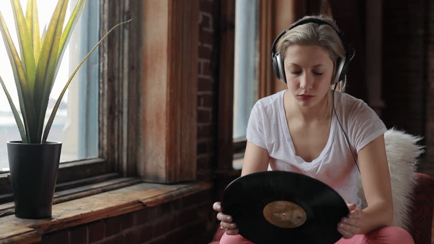 Beautiful Teen Wearing Headphones Listens To Music And Looks At Her Record