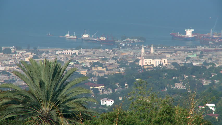 Port-au-Prince, Haiti - Jan 2009:  View of a cargo ship ships at the docks on the coast of the Haitian capital city of Port-au-Prince.  Catholic cathedral and palm trees visible in the foreground.