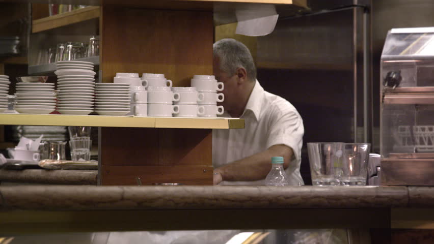 Static shot of a man working in the back of an Italian cafe.