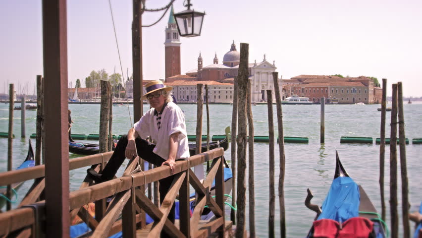A Gondolier waits on a dock on the Grand Canal in Venice, Italy.