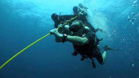 COLOMBO, SRI LANKA - FEB 23: Scuba divers holding onto anchor rope in strong current while making safety stop on ascent on February 23, 2014 in Colombo, Sri Lanka