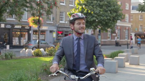 Businessman riding bike through urban park.Shot on Canon 5D MkII at a frame rate of 25fps