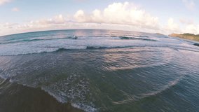Aerial Slow Motion Shot of Surfers Paddling out During a Perfect Sunset on a Secret Beach in Kauai Hawaii - HD 1080 Video in Slow Motion with Golden Water Low Flying Pan Over the Ocean 