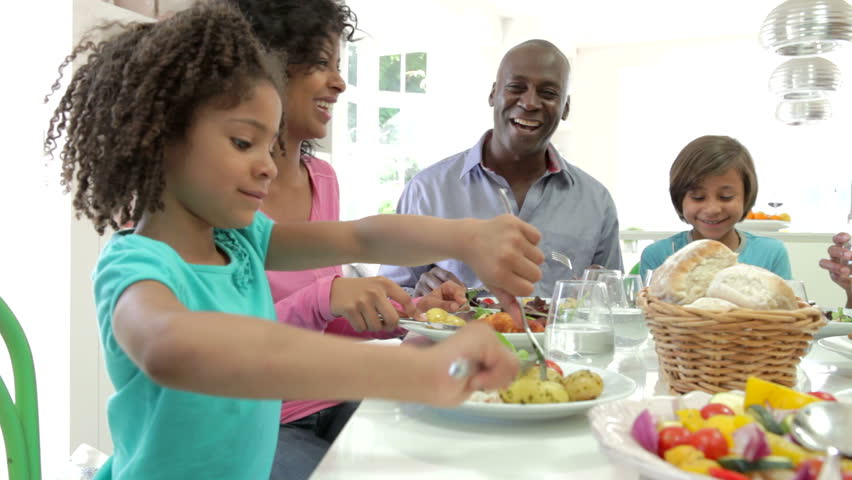 Extended African American family sitting around table at home eating meal together.Shot on Canon 5d Mk2 with a frame rate of 25fps