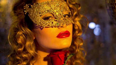 beautiful sexy female in fantastic gold catsuit in lounge bar setting with mask and a rose. Useful for parties, clubs and events
