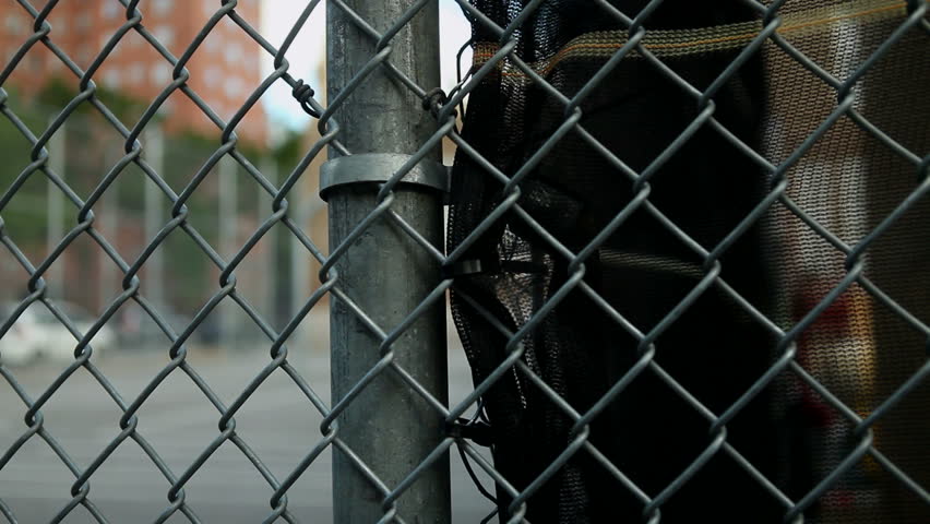 Dolly and rack focus from fence to basketball goal in a schoolyard