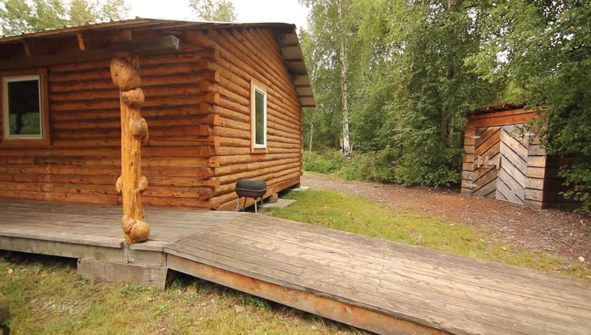 Nature Trees Cabin. Log cabin with large natural pillars with lush vegetation in background.