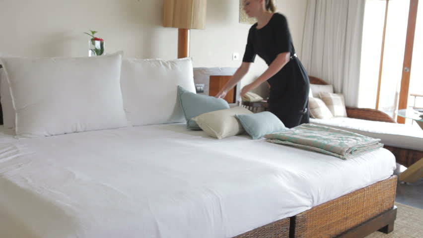 Chambermaid arranges cushions in hotel bedroom.Shot on Canon 5d Mk2 with a frame rate of 30fps