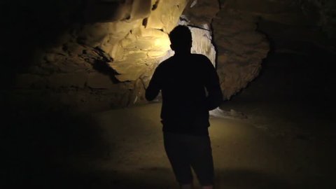 Teenager walking through a giant cave. exploring on journey silhouetted. 
