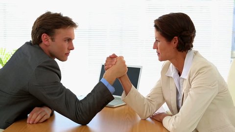 Business people arm wrestling at desk in the office
