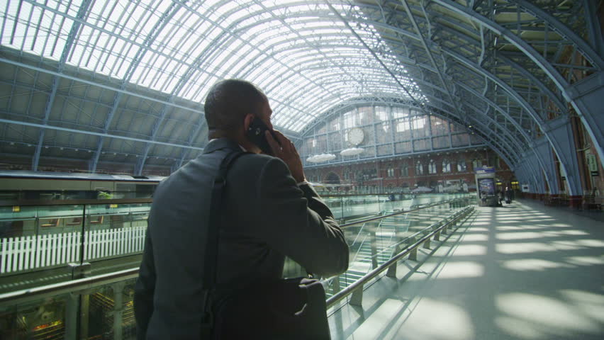Businessman makes a phone call as he walks through iconic London railway station Royalty-Free Stock Footage #5895194