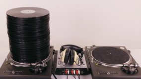 a large pile of records grows and shrinks on two dj turntables