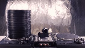 a large pile of records grows and shrinks on two dj turntables