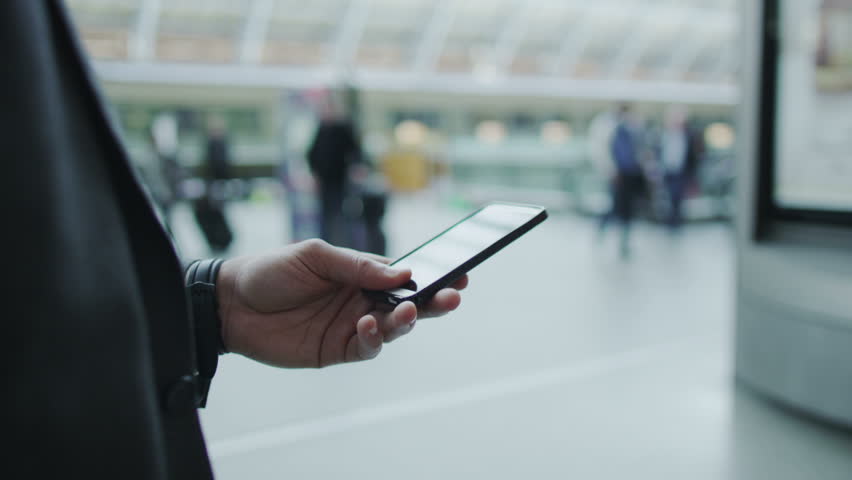 Businessman looking at his phone as he walks through a busy railway station. Royalty-Free Stock Footage #5897543