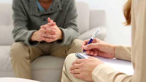 Young man sitting on sofa talking to his therapist at therapy session