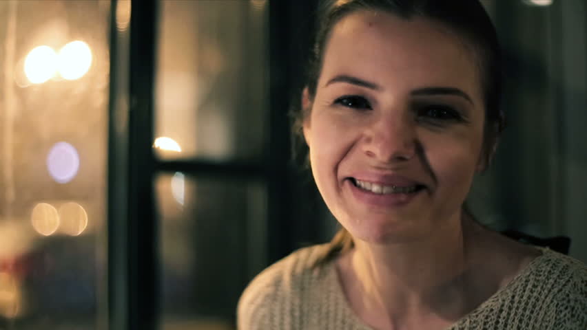 Happy beautiful woman smiling to camera, bar, night time

