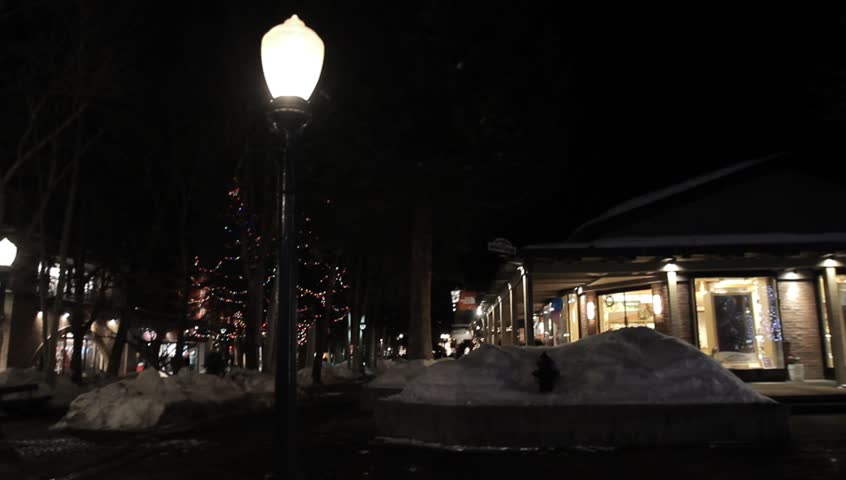 Lights Trees Aspen Colorado Town. Illuminated, colorful lights displayed on rows of trees near people walking on a pathway and entering buildings in Aspen, Colorado. Also includes holiday lights.