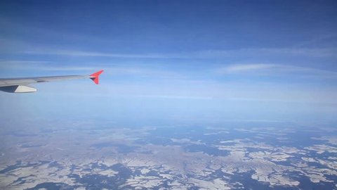 flying over ice fields, snowy landscape. View from plane side window with the wing (hd, 1920x1080, 1080p, high definition, hidef) Traveling by air. View through an airplane window.
