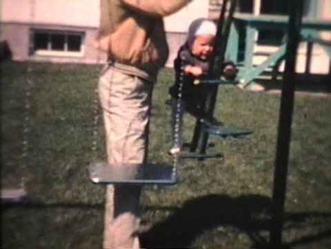A little boy has fun on the swings in his backyard.