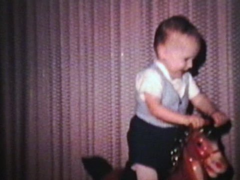 A cute little boy rides his horsey at top speed in the family living room.