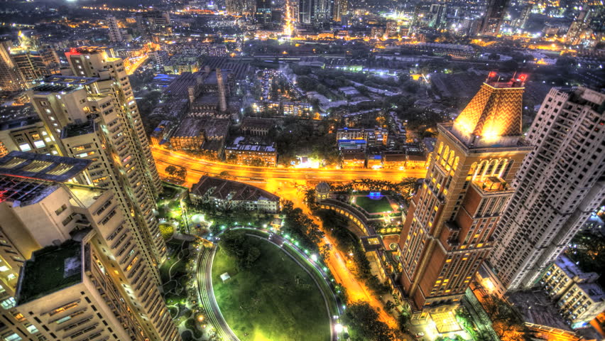 high angle aerial view HDR time lapse of Mumbai traffic and city. the shot tilts up, transition from day to night. each frame is a fusion of 3 exposures.