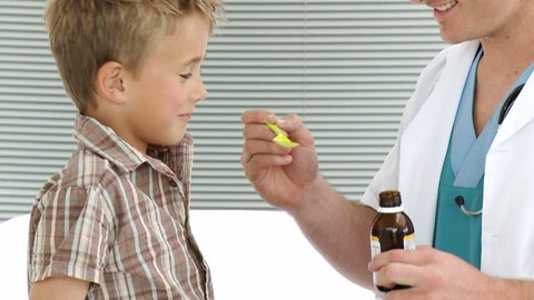 Child taking cough medicine in medical office