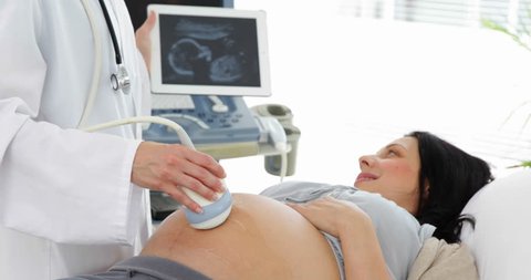 Brunette pregnant woman having a sonogram scan in office at the hospital