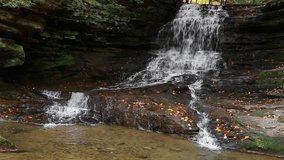 Honey Run Falls, a waterfall near Millwood in Knox County, Ohio, splashes down a rocky cliff with autumn foliage in this seamlessly looping video footage.